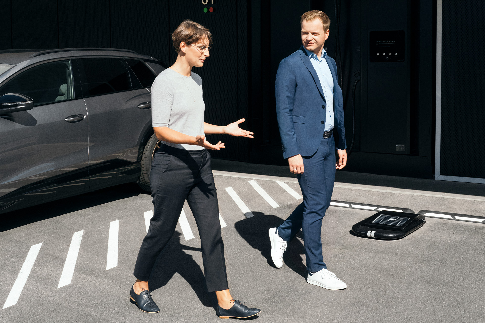  Los expertos en sustentabilidad, la Dra. Johanna Klewitz y Malte Vömel, caminan por el estacionamiento frente al centro de carga de Audi en Nuremberg.